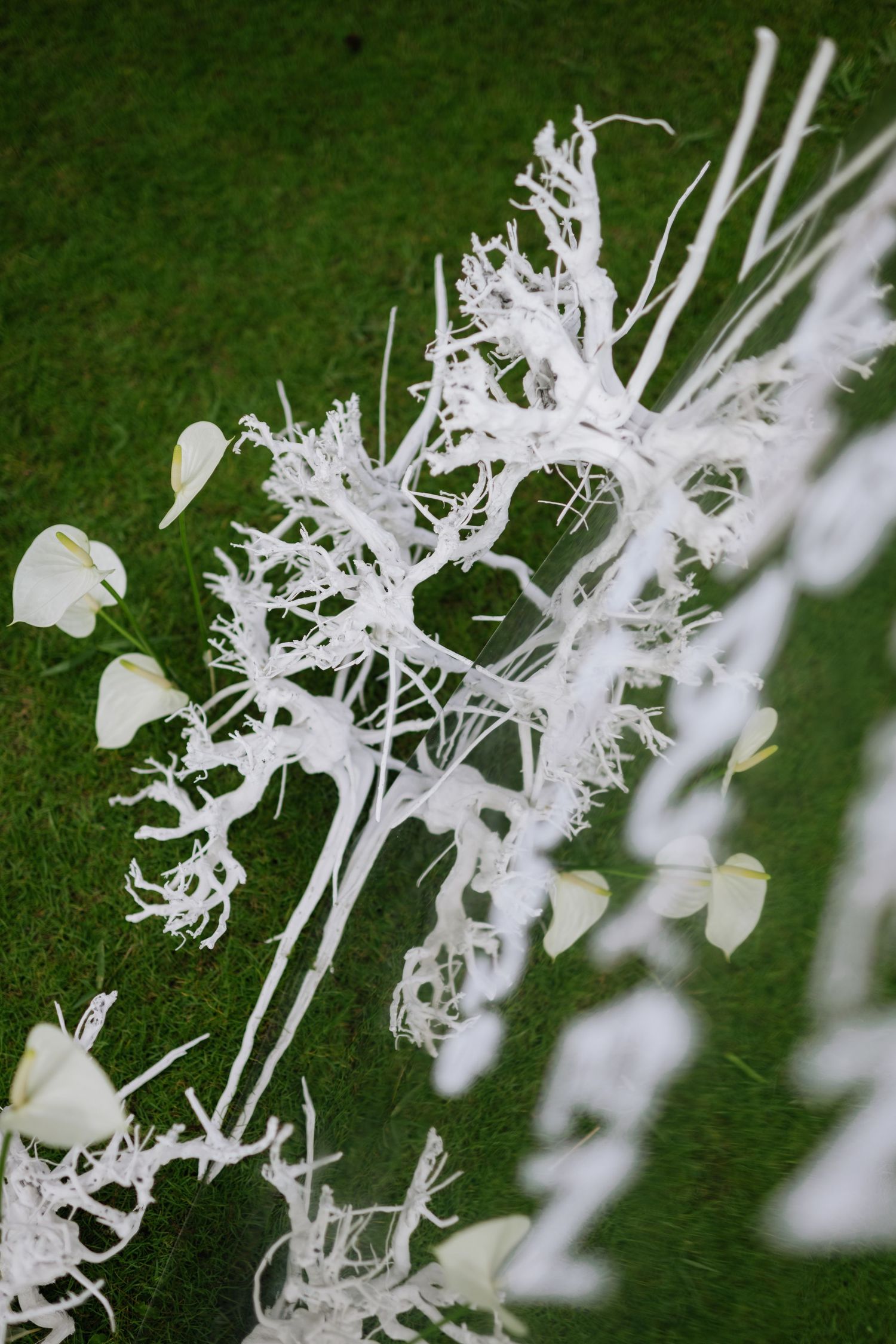 White decorative branches with small white flowers and leaves arranged on green grass for wedding decor.