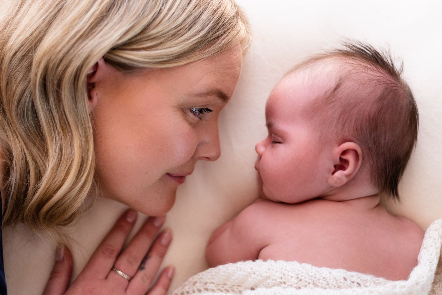 Intimate close-up of parent and baby lying face to face.