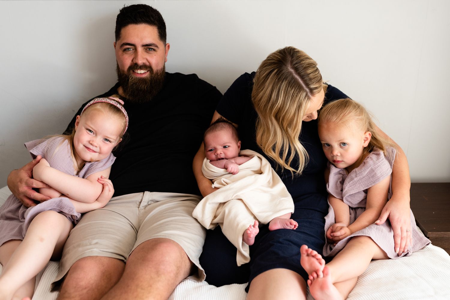 Happy family sitting together on couch with three young children.