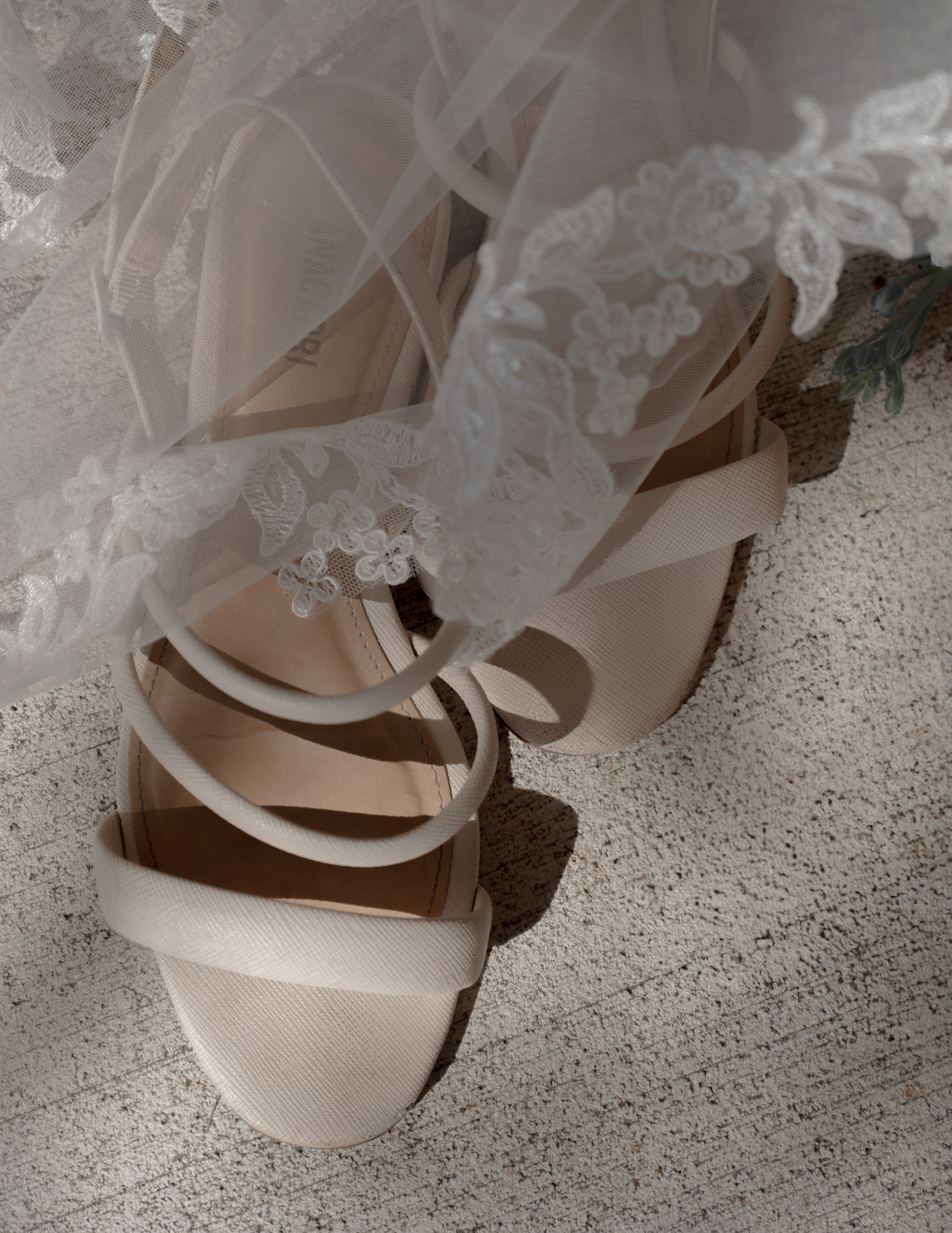 Close-up details of elegant white bridal shoes and lace dress hem.