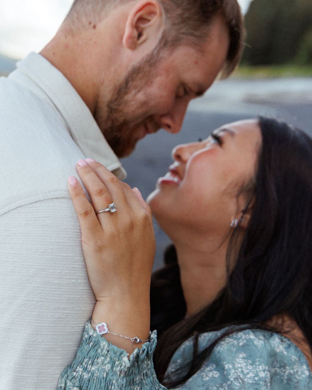 Close-up of couple sharing intimate moment in white and floral blue dress with mountains in background.
