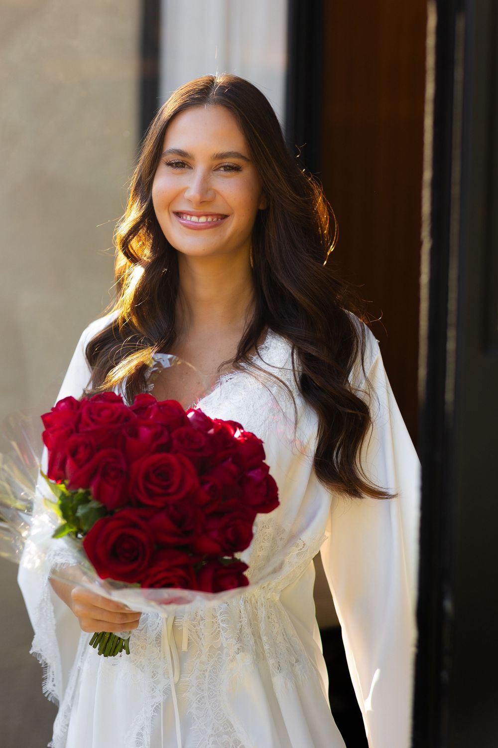 Four photos of someone in a white dress holding vibrant red rose bouquets in an outdoor setting.