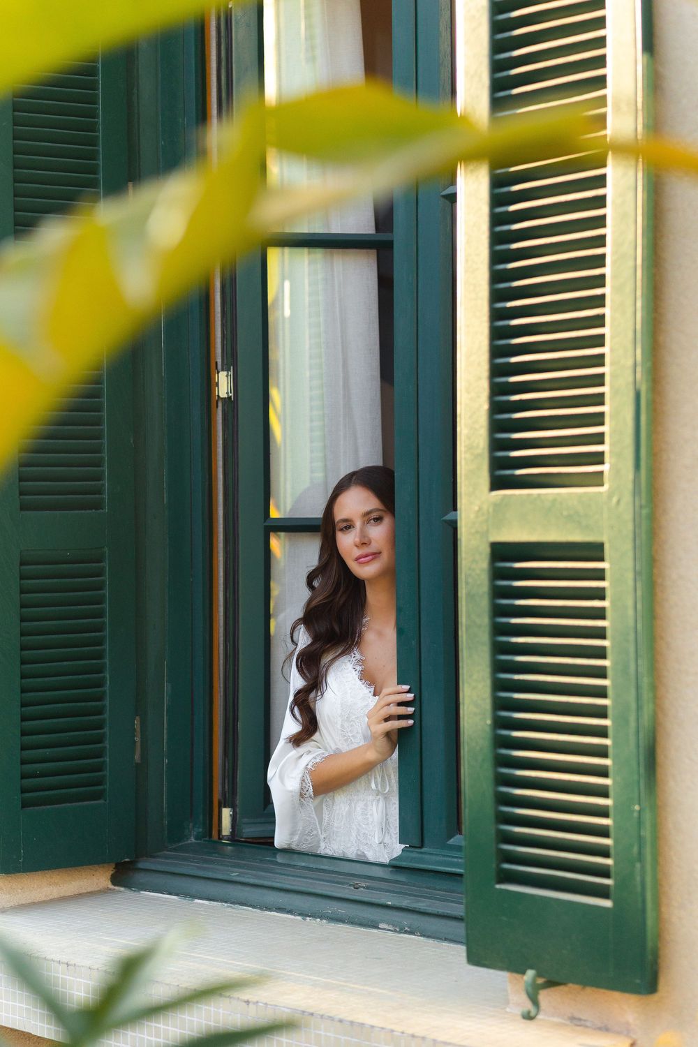 Woman in white dress leans out of window with green shutters, creating artistic triptych composition.