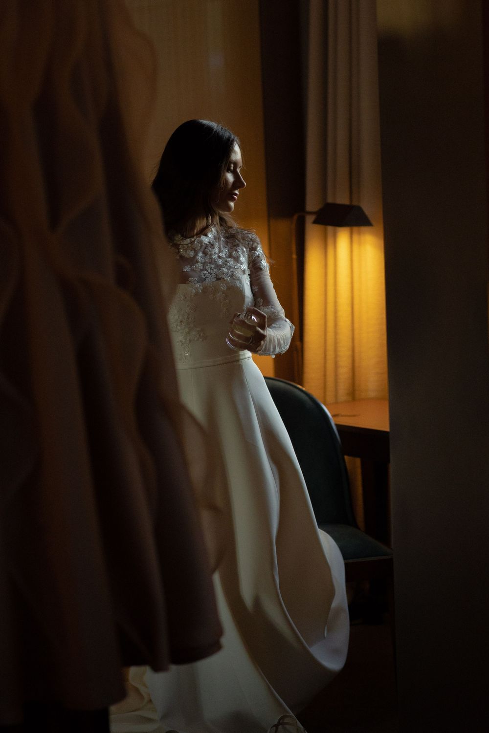 Romantic wedding portrait of couple dancing together in a dimly lit room with soft lighting.