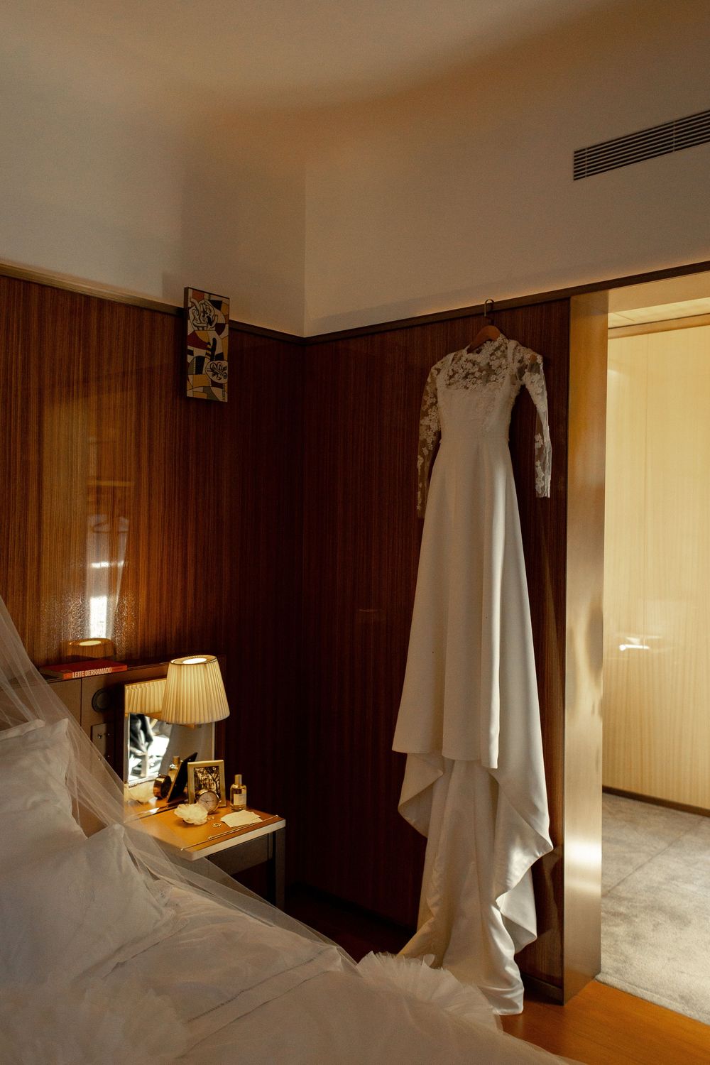 A dimly lit hotel room interior with cream walls, dark wood paneling, and white hanging bath robes showing multiple angles.