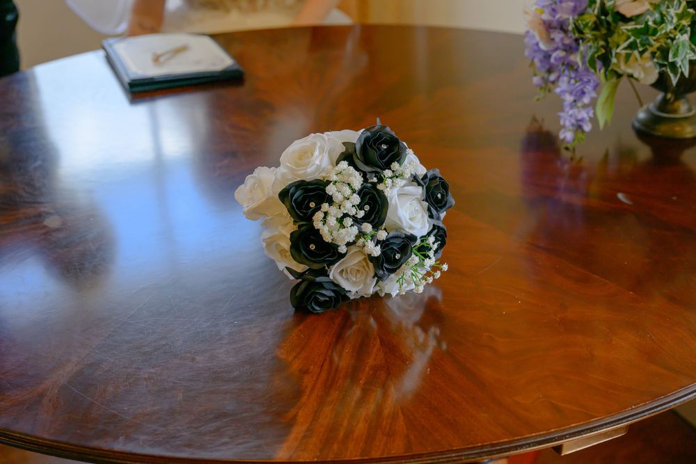 White and ivory floral wedding bouquet rests on polished wooden table surface.