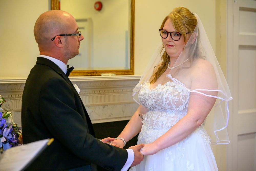 A couple shares a tender moment during their wedding ceremony in an elegant indoor setting.
