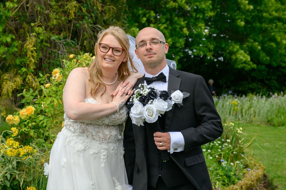 A romantic wedding photo shoot in a lush garden setting with vibrant greenery and summer blooms.