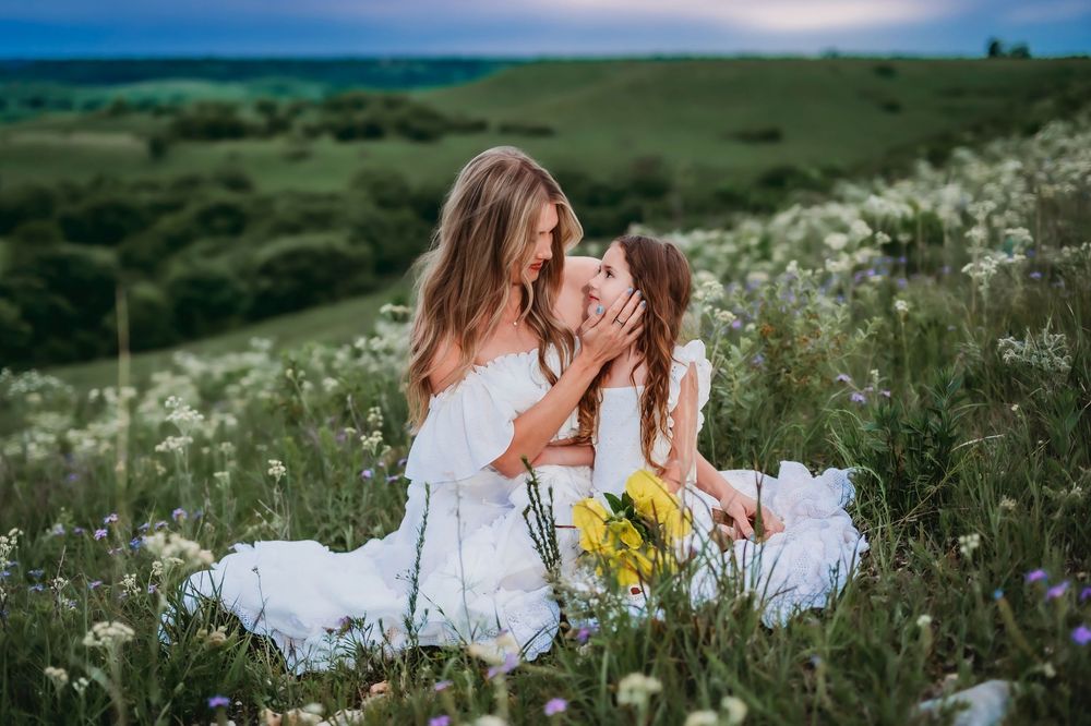 A dreamy field of white wildflowers and tall grass sways in the breeze against a pastel sunset sky.