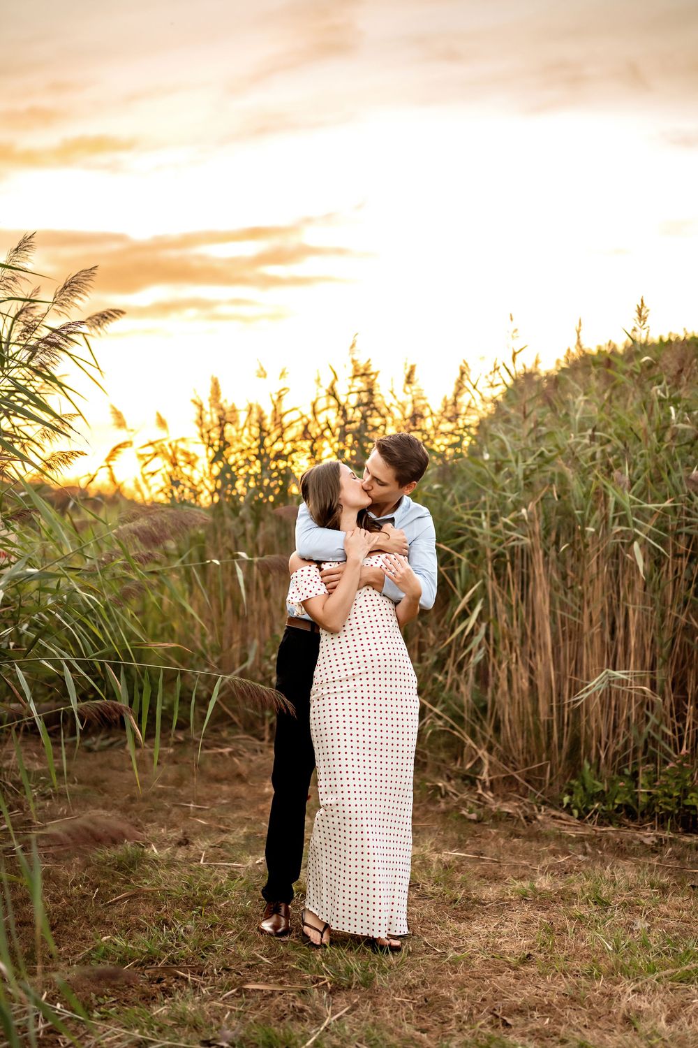 A couple shares an intimate moment at sunset in a field of tall grass and sugarcane.