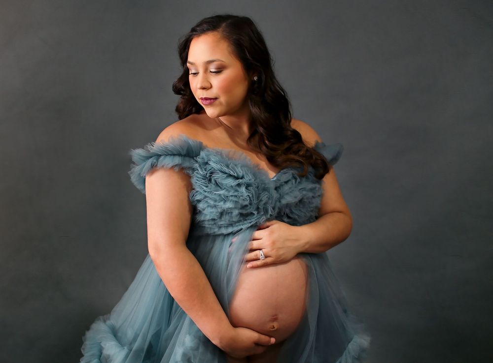 Mama posing in a beautiful maternity dress with hands on her belly