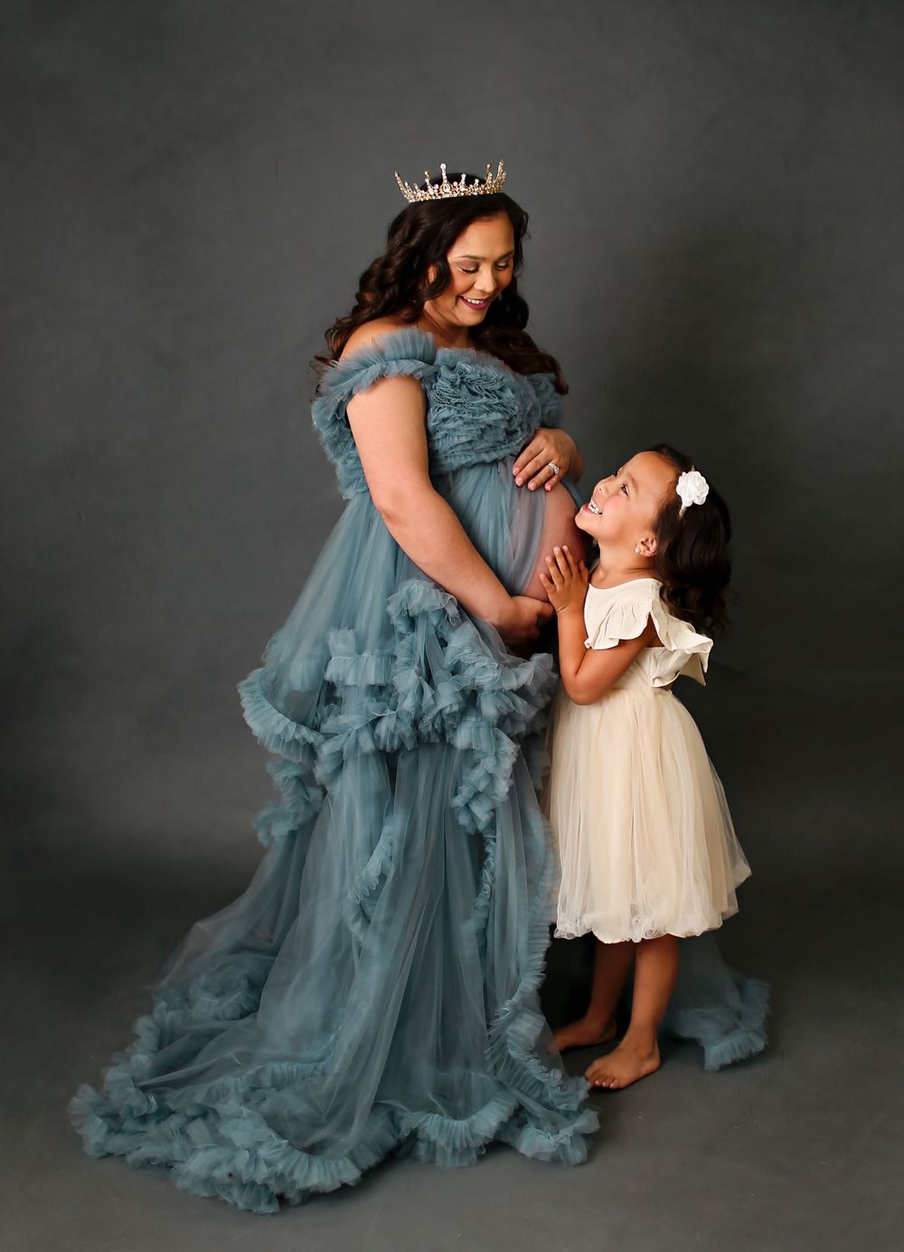 Pregnant mama posing with oldest daughter for maternity session as her and her oldest snuggle her belly and look at each other