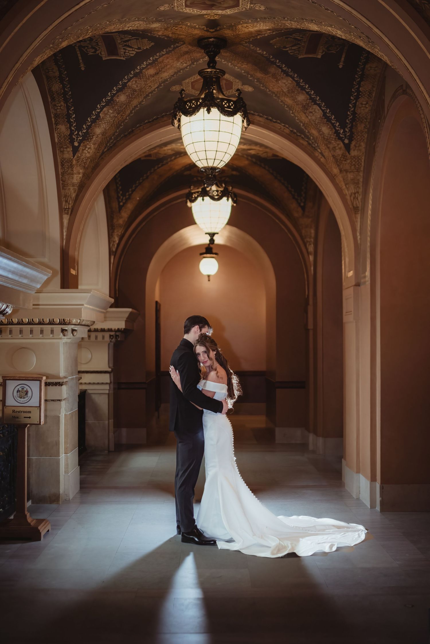 An aerial view of a couple in formal attire beneath an elegant curved staircase.