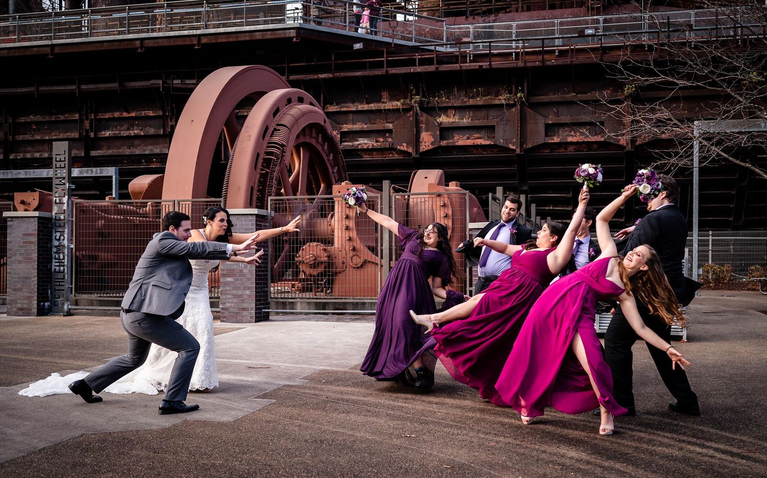 Wedding party dancing and posing dramatically on an outdoor wooden deck.