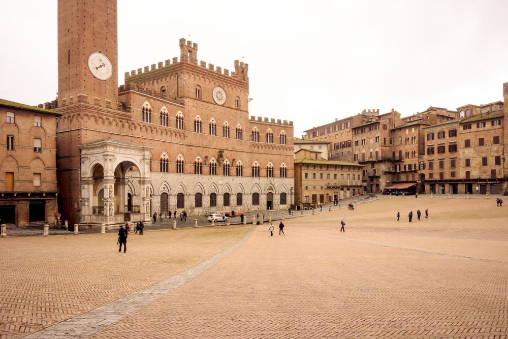 A panoramic view of Piazza del Campo in Siena, Italy, showing historic medieval architecture and cobblestone pavement.