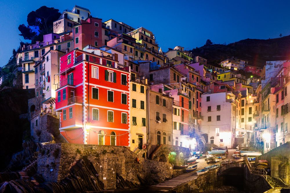 Stunning panoramic view of colorful houses along the Italian Riviera coastline at dusk in Riomaggiore, Cinque Terre.