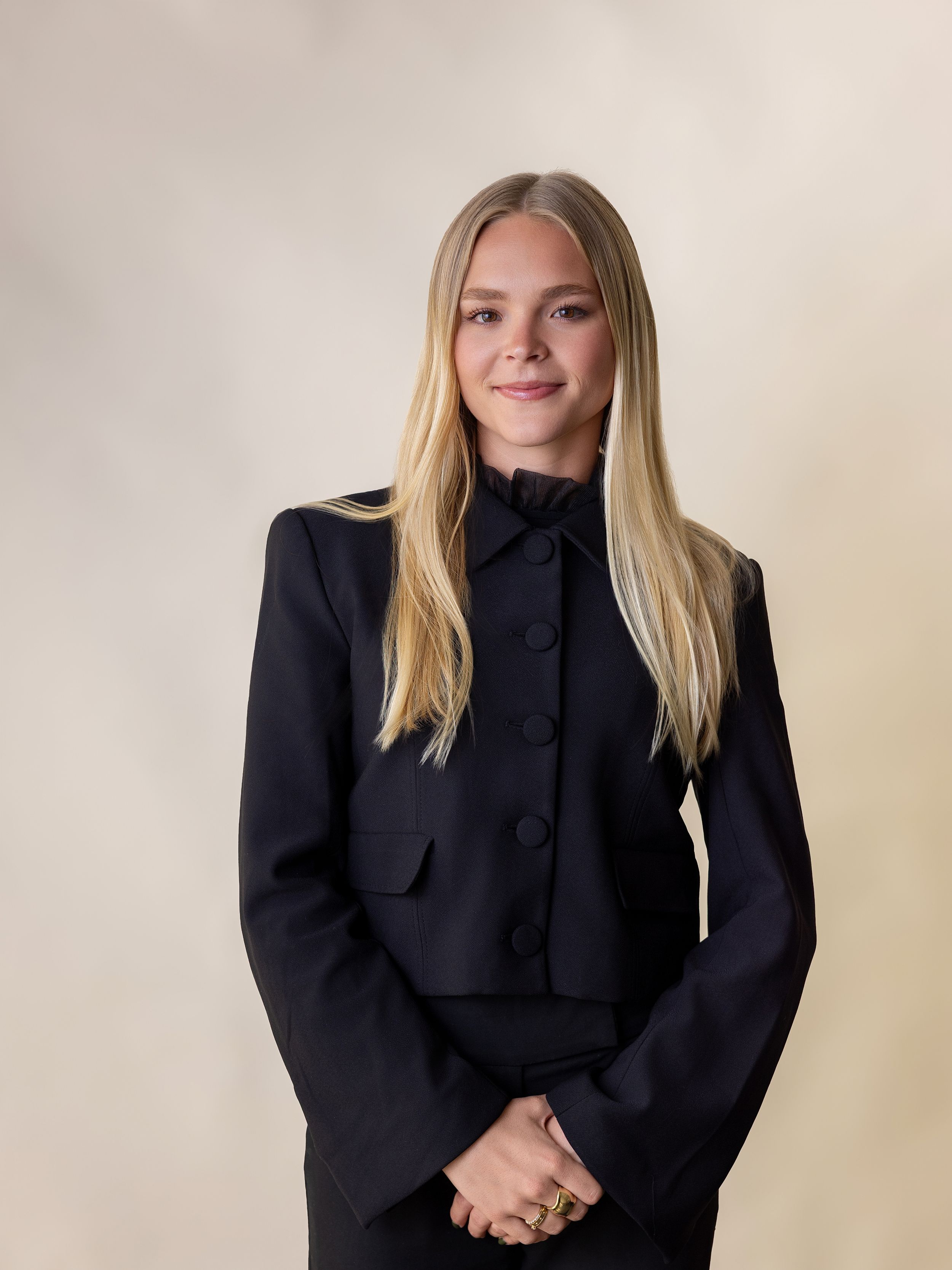 A person wearing a black turtleneck sweater posing in a series of professional headshots against a light background.
