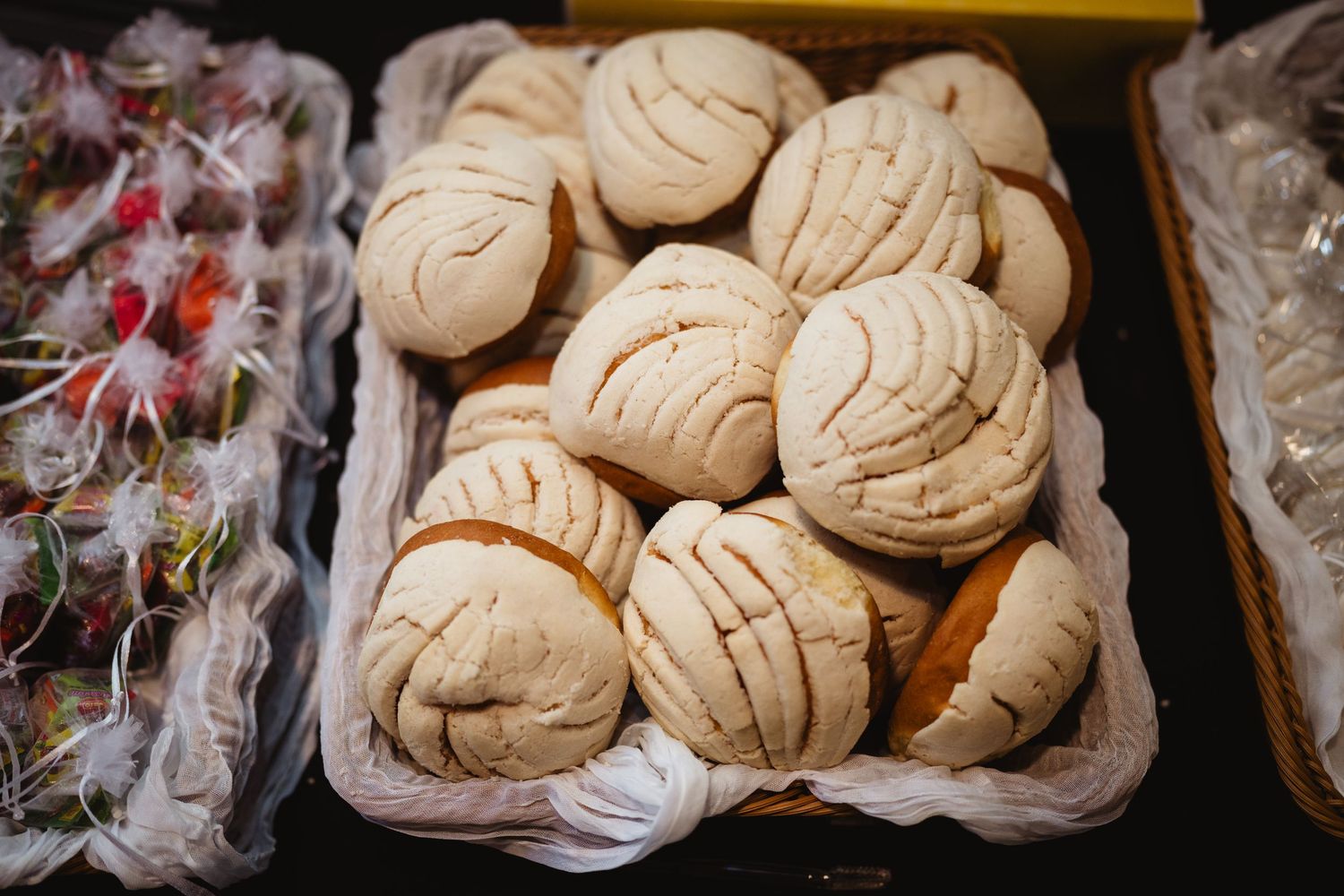 Fresh baked conchas, traditional Mexican sweet bread rolls, arranged in a bakery display case.