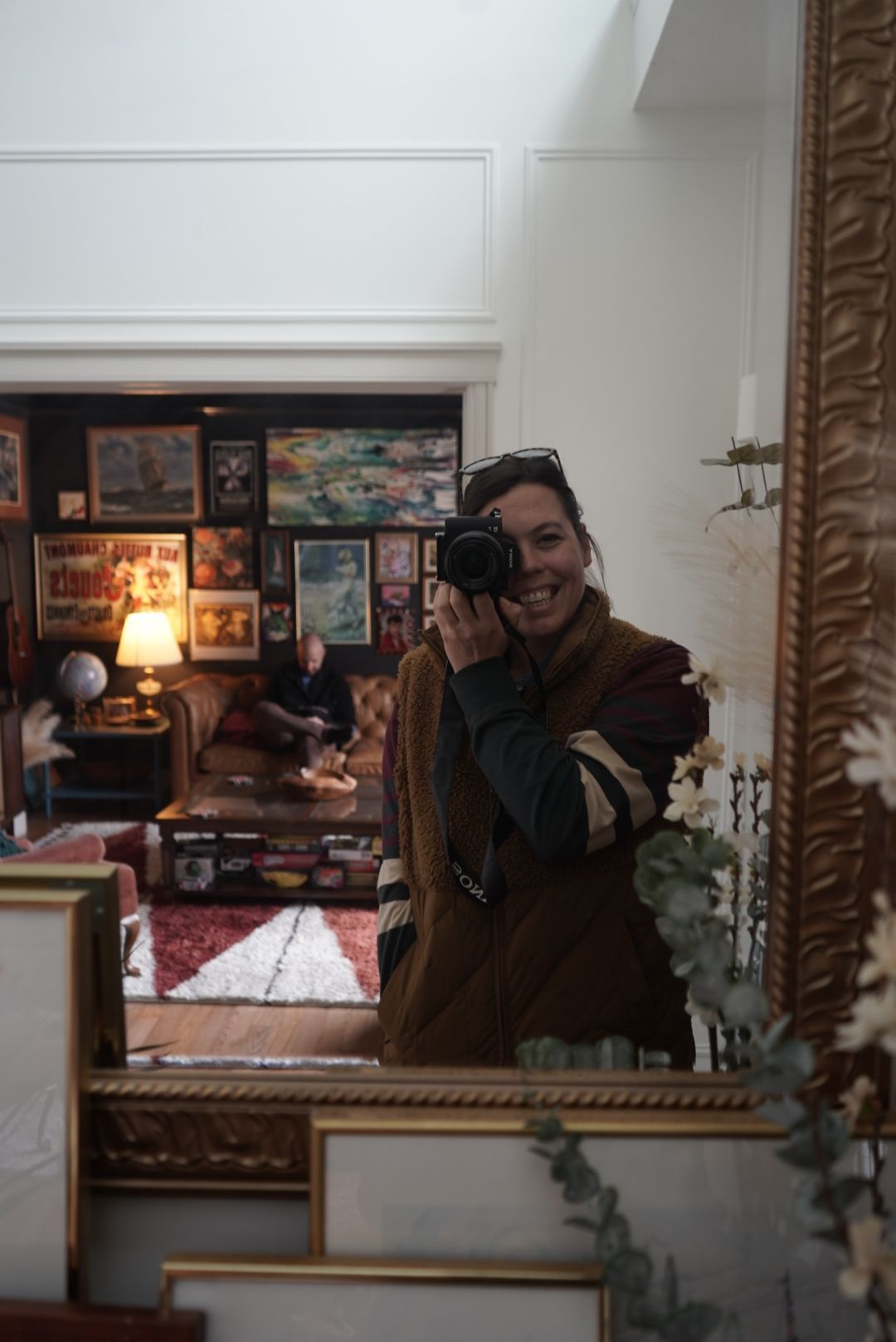 mirror self portrait of a person holding a camera in an ornately framed mirror.