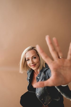 Woman in denim jacket makes playful hand gestures in studio portrait sequence.