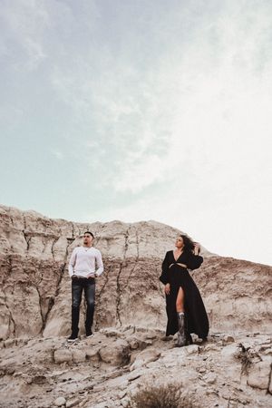 Couple poses playfully on desert rock formations in casual attire.