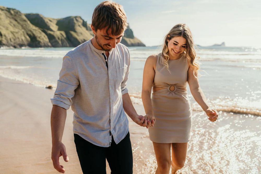 A couple walks hand in hand along a scenic beach at sunset, creating romantic silhouettes against the golden light.