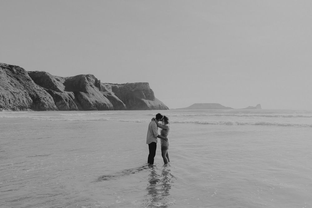 Black and white beach photographs arranged in sequence showing a couple walking together along the shoreline.