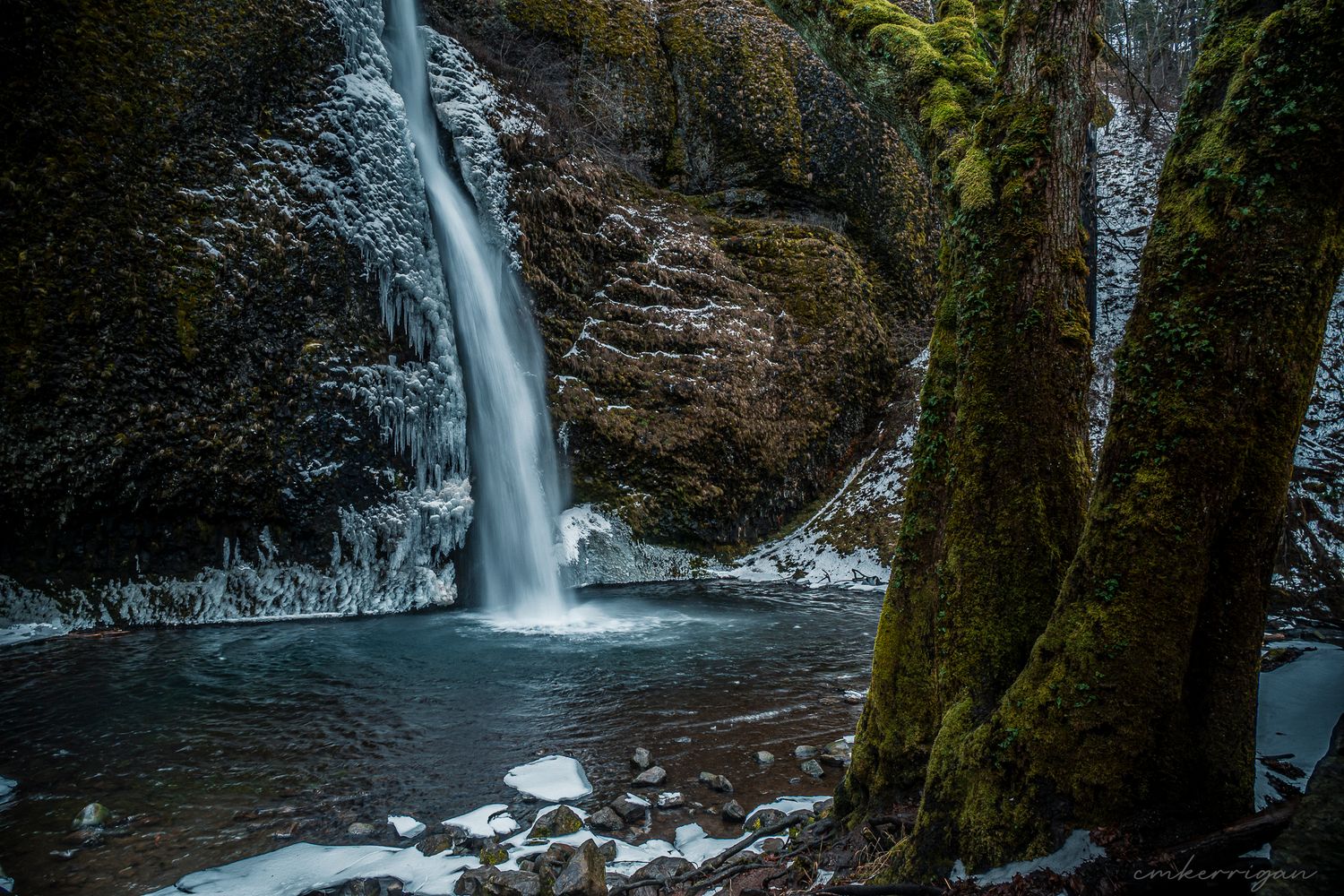 A majestic waterfall cascades down moss-covered rocks in a lush forest setting creating a peaceful natural scene.