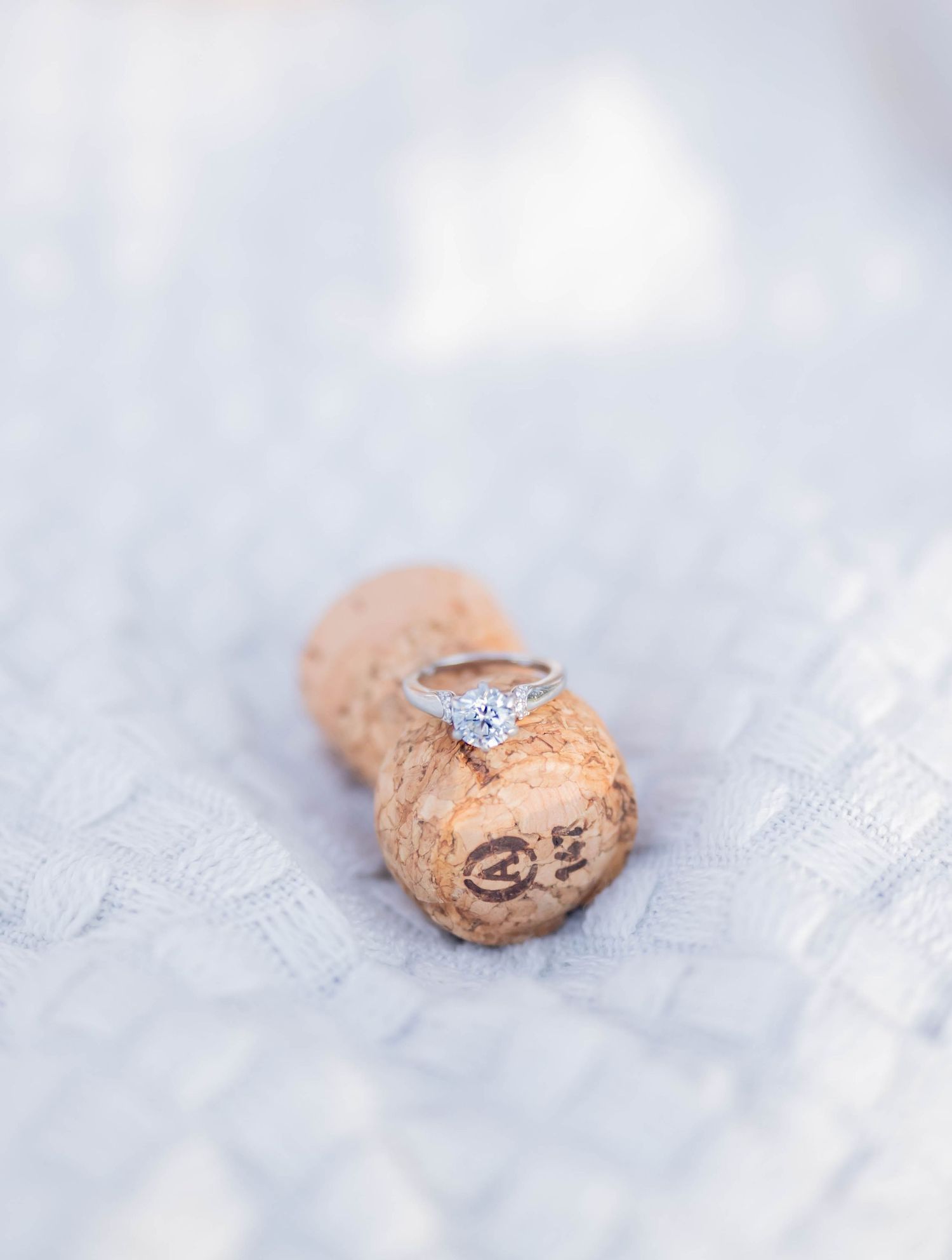 Four elegant engagement rings with sparkling diamonds on a soft gray textured background in progressive display.