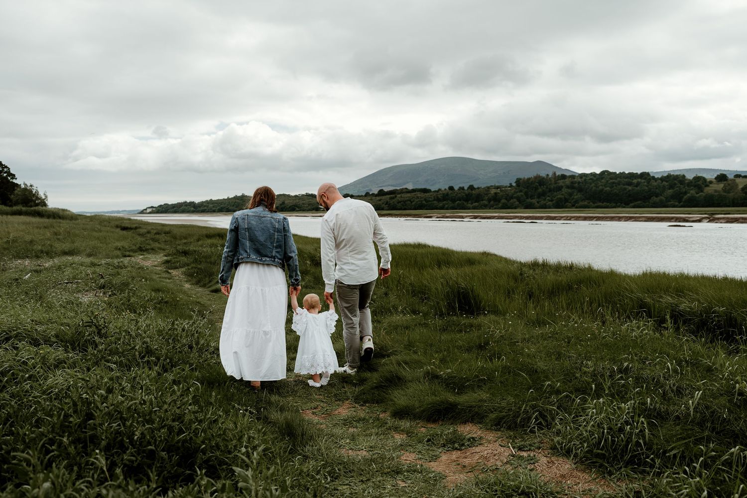 Family walking away during photoshoot with dramatic landscape in background of Dumfries