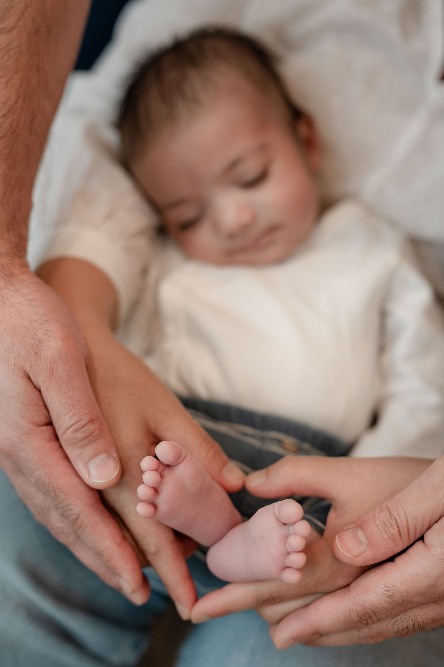 A collection of images showing gentle hands holding and caressing tiny baby feet on white bedding.