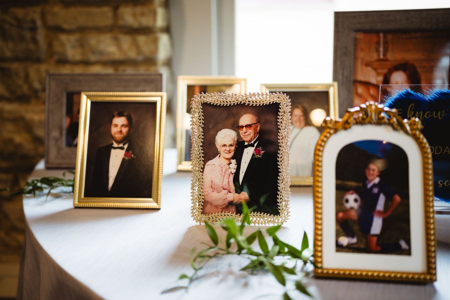 Wedding reception venue with elegant gold frames and portraits adorning stone walls in warm lighting.