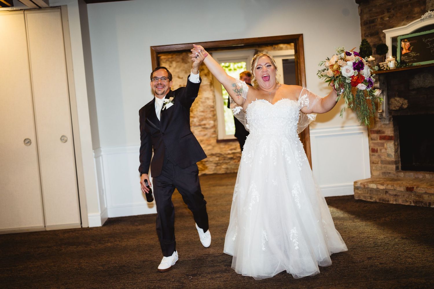 Wedding party members walk together down a rustic hallway lit by wall sconces.