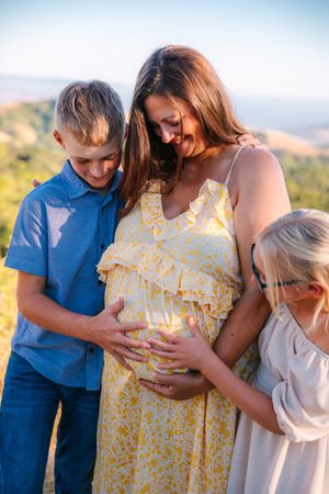 Family members gather around embracing in an outdoor setting with golden sunset lighting.