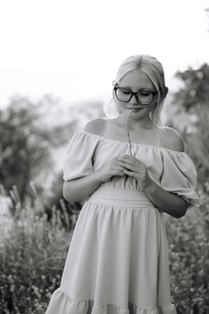 Black and white photos show a figure in a flowing white dress standing among wildflowers in a dreamy garden setting.