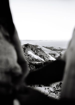 Panoramic black and white view of snow-covered mountain peaks against a misty sky in a dramatic alpine landscape.