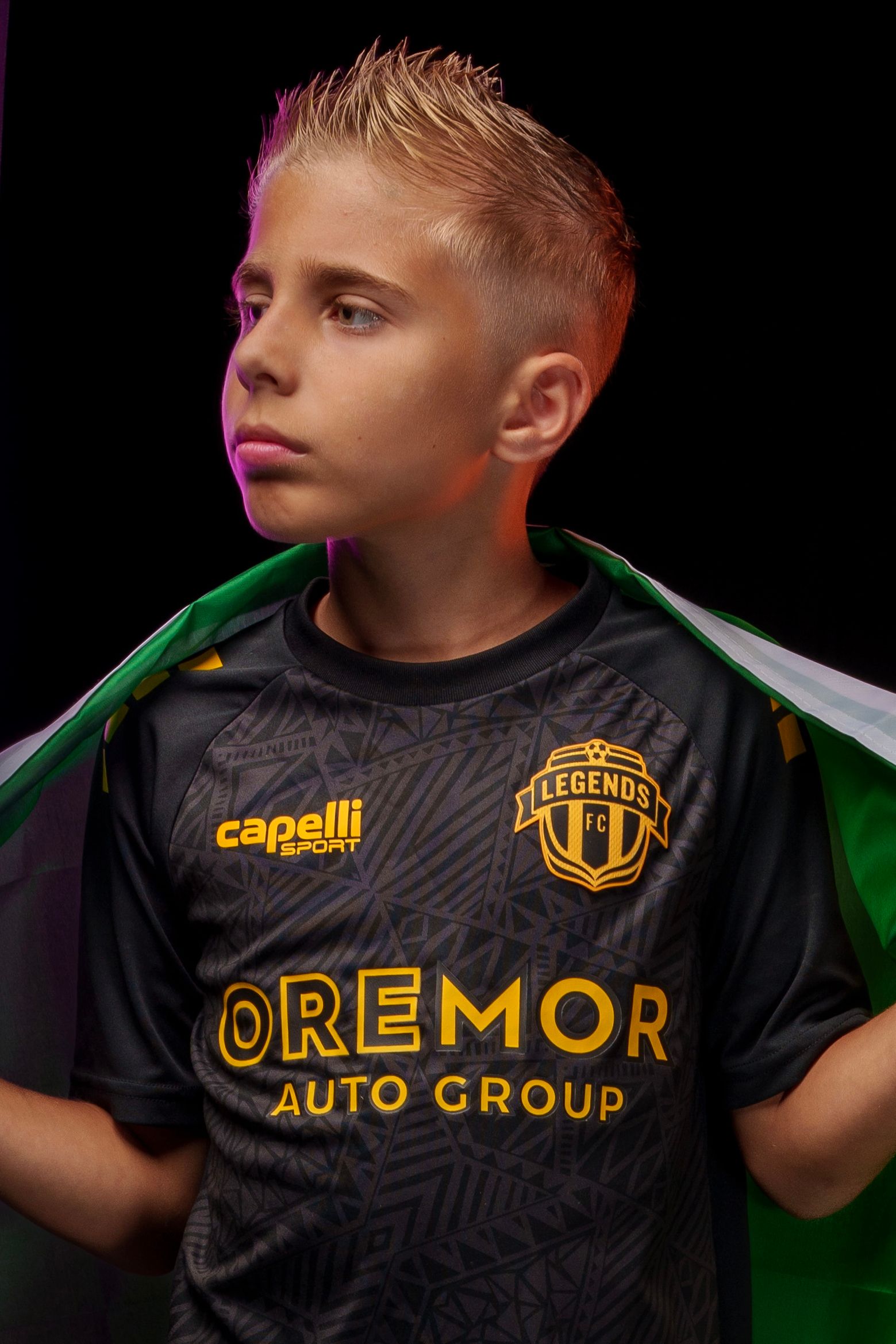 Youth soccer player in black Legends FC jersey with gold text against dark background.