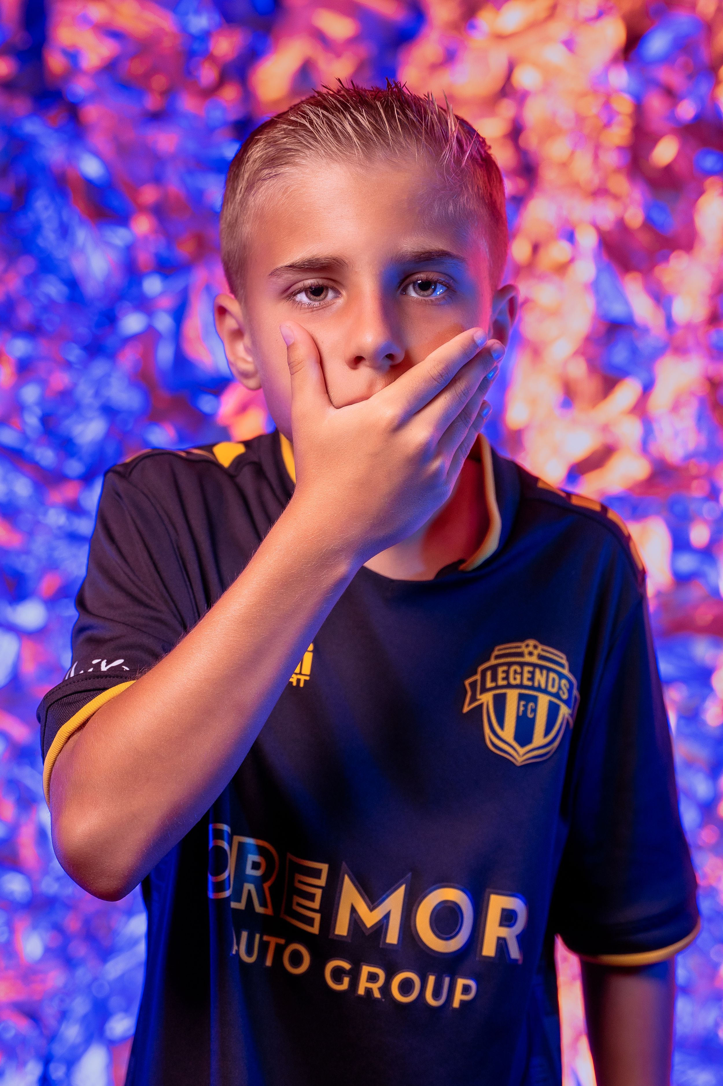 Athletic poses in black Legends FC jersey with colorful lighting effects.