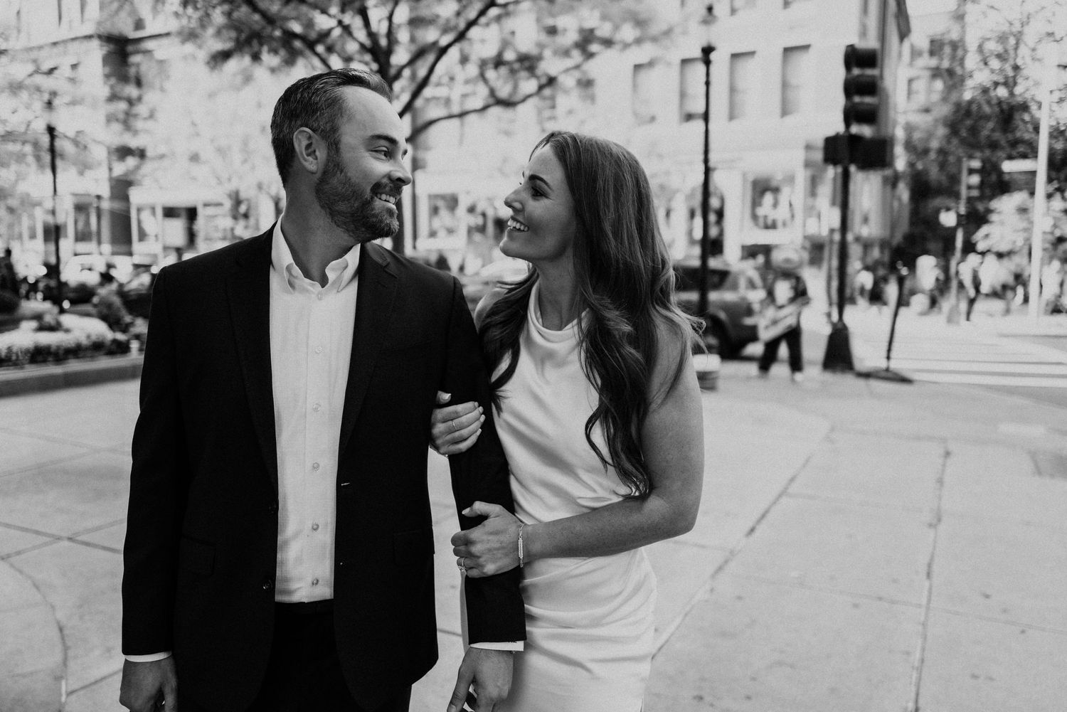 Black and white urban street photography of a couple walking and laughing together.