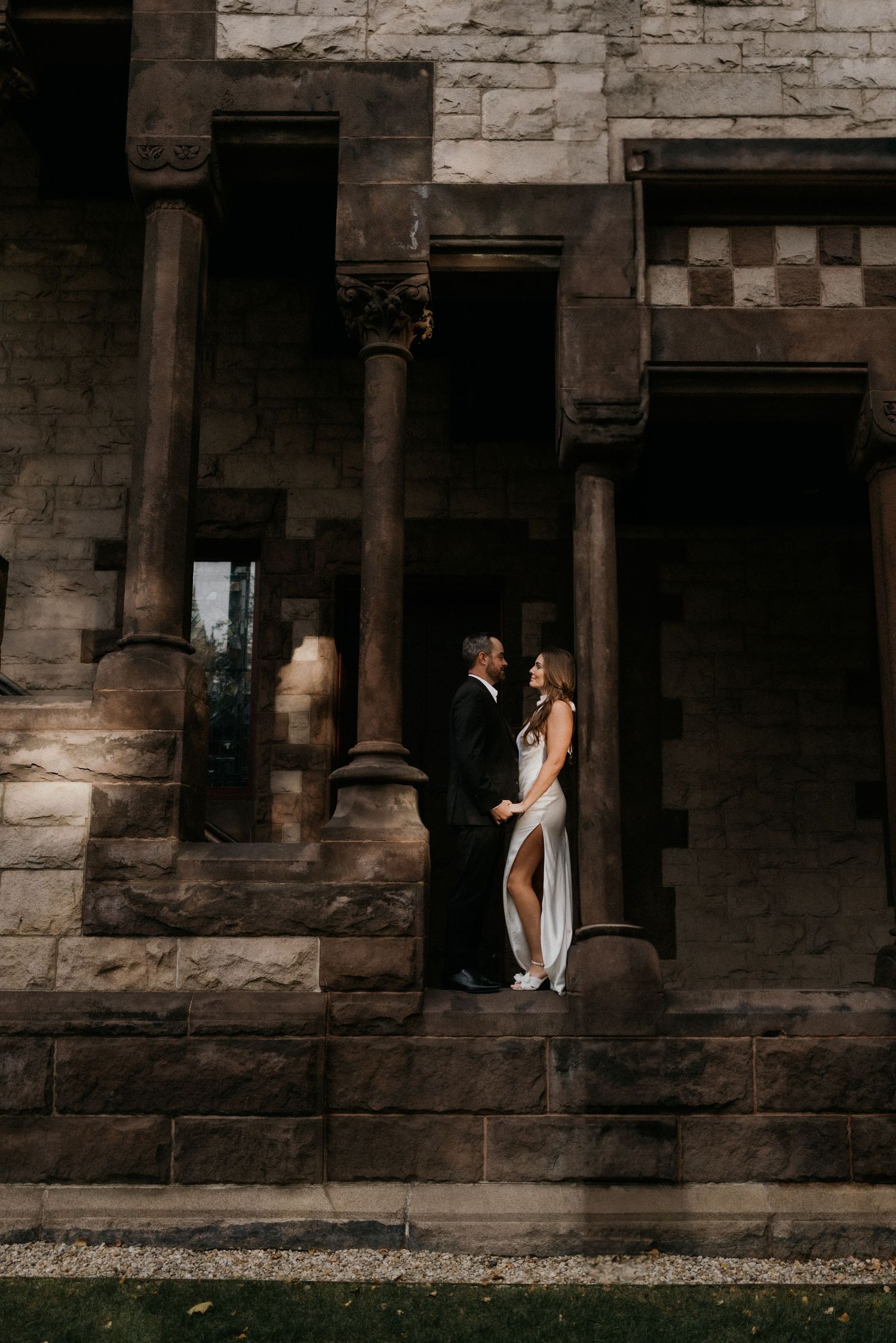 Dramatic moody portrait series against a rustic stone wall featuring white flowing fabric and architectural columns.