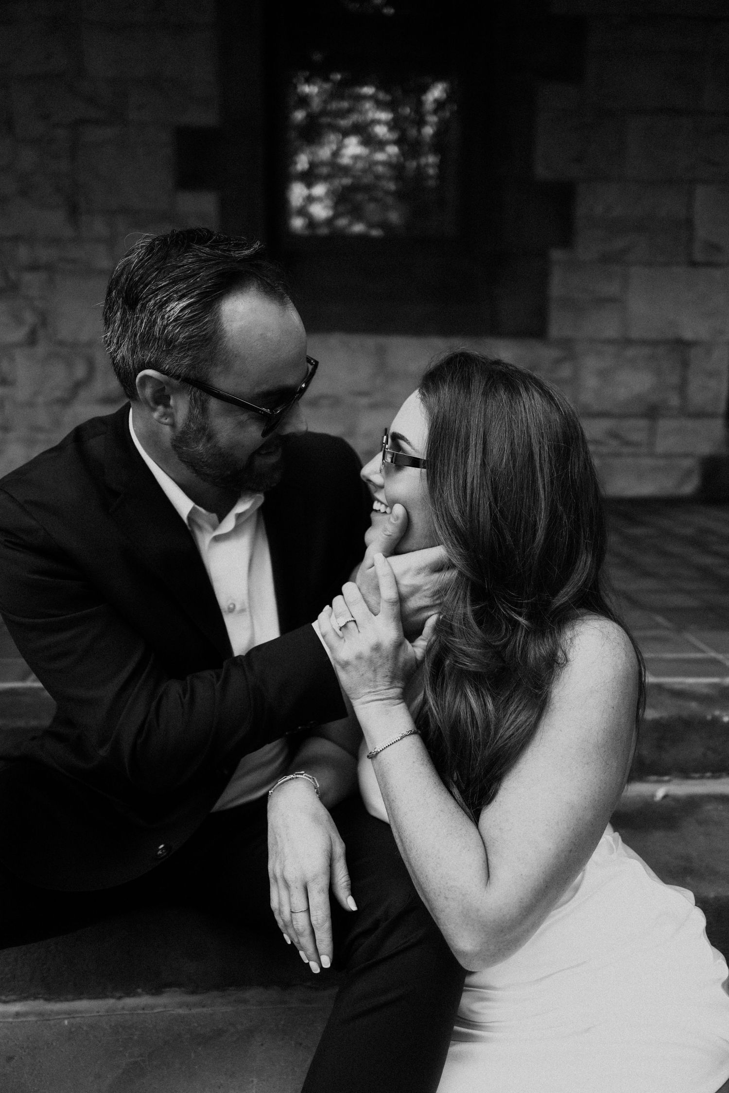 Intimate black and white portrait of a couple sharing a tender moment on stone steps.