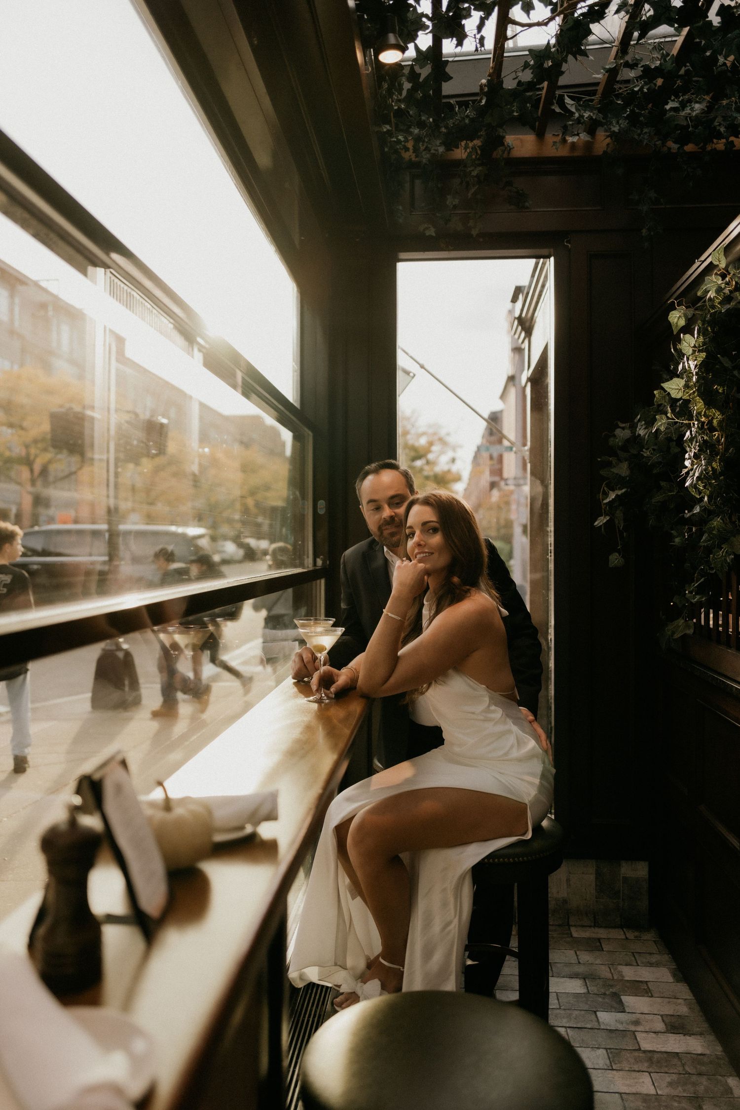 Couple shares a joyful moment together at a restaurant bar with warm sunset lighting streaming through windows.