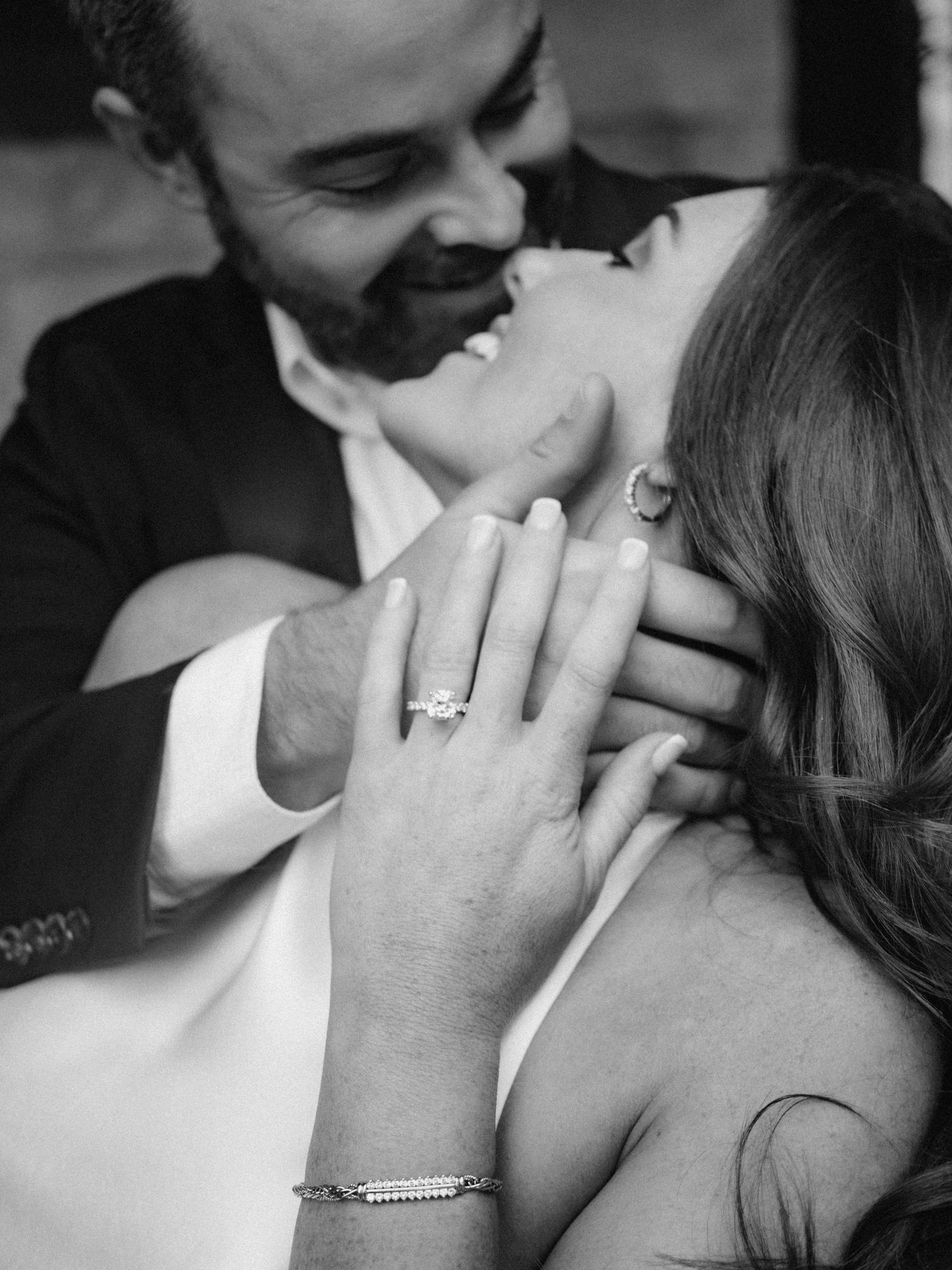 A romantic black and white engagement photo showing a close intimate moment and sparkling diamond ring.