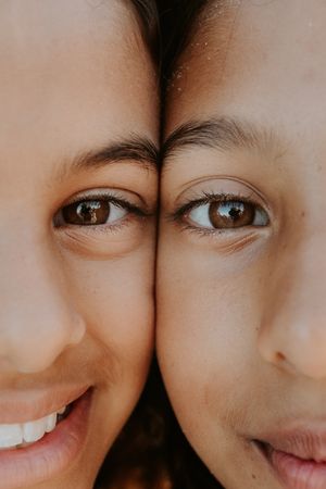 A close up shot of two sisters faces side by side showcases their resemblance and features during Adelaide family photo session at sunrise.
