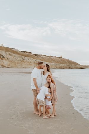 A gorgeous family of five huddle on a sandy south Adelaide beach at sunrise during a fun photo session with Lauren Lunn Photography.