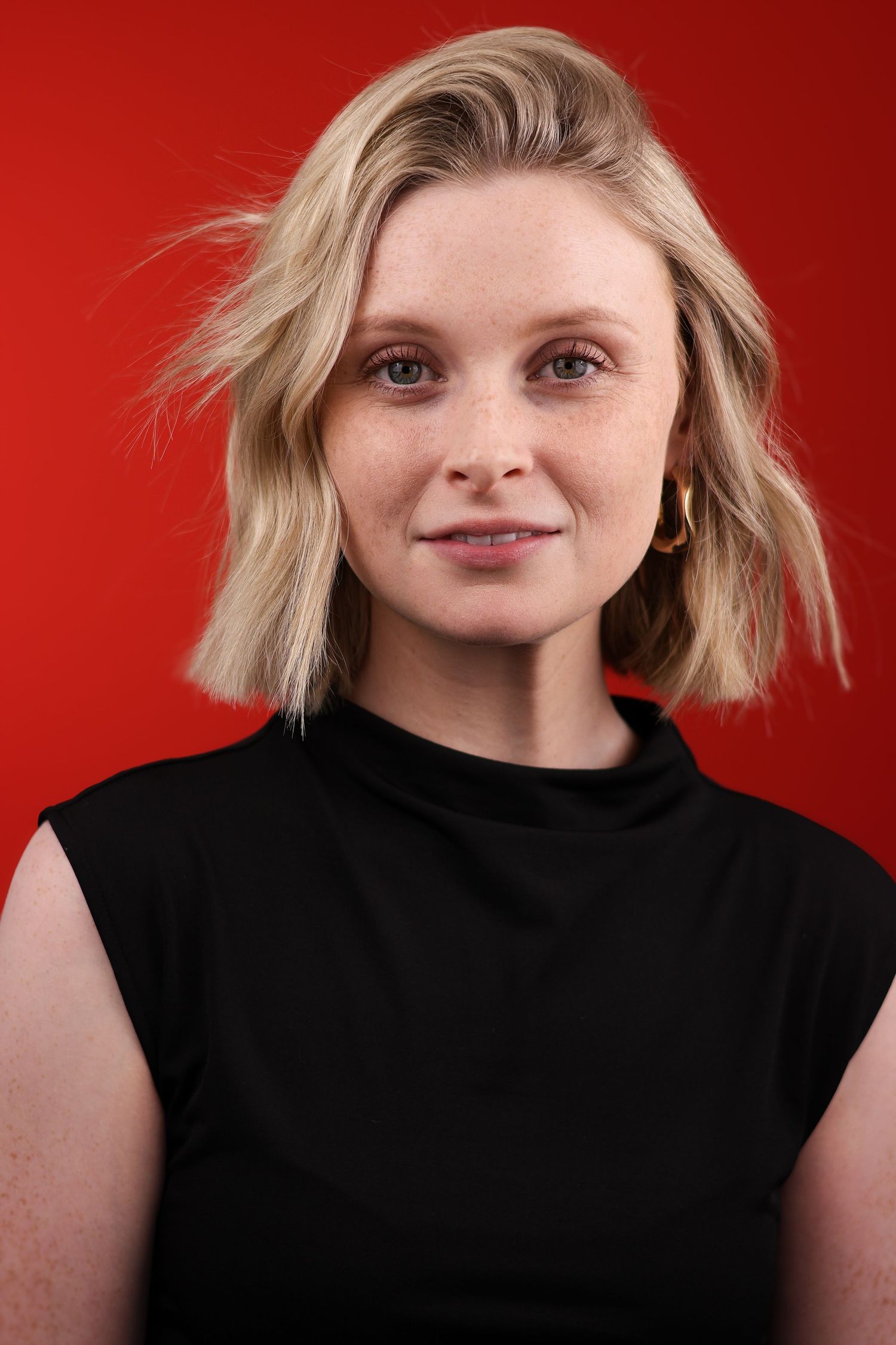 Portrait series of a person in a black sleeveless top against a vibrant red background showing various expressions.