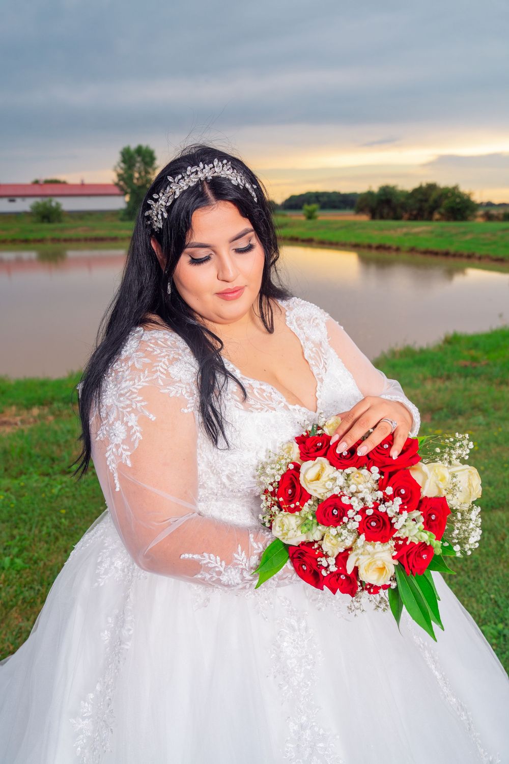 Bride with red rose bouquet poses by lakeside during golden hour. Appleton Photographer.