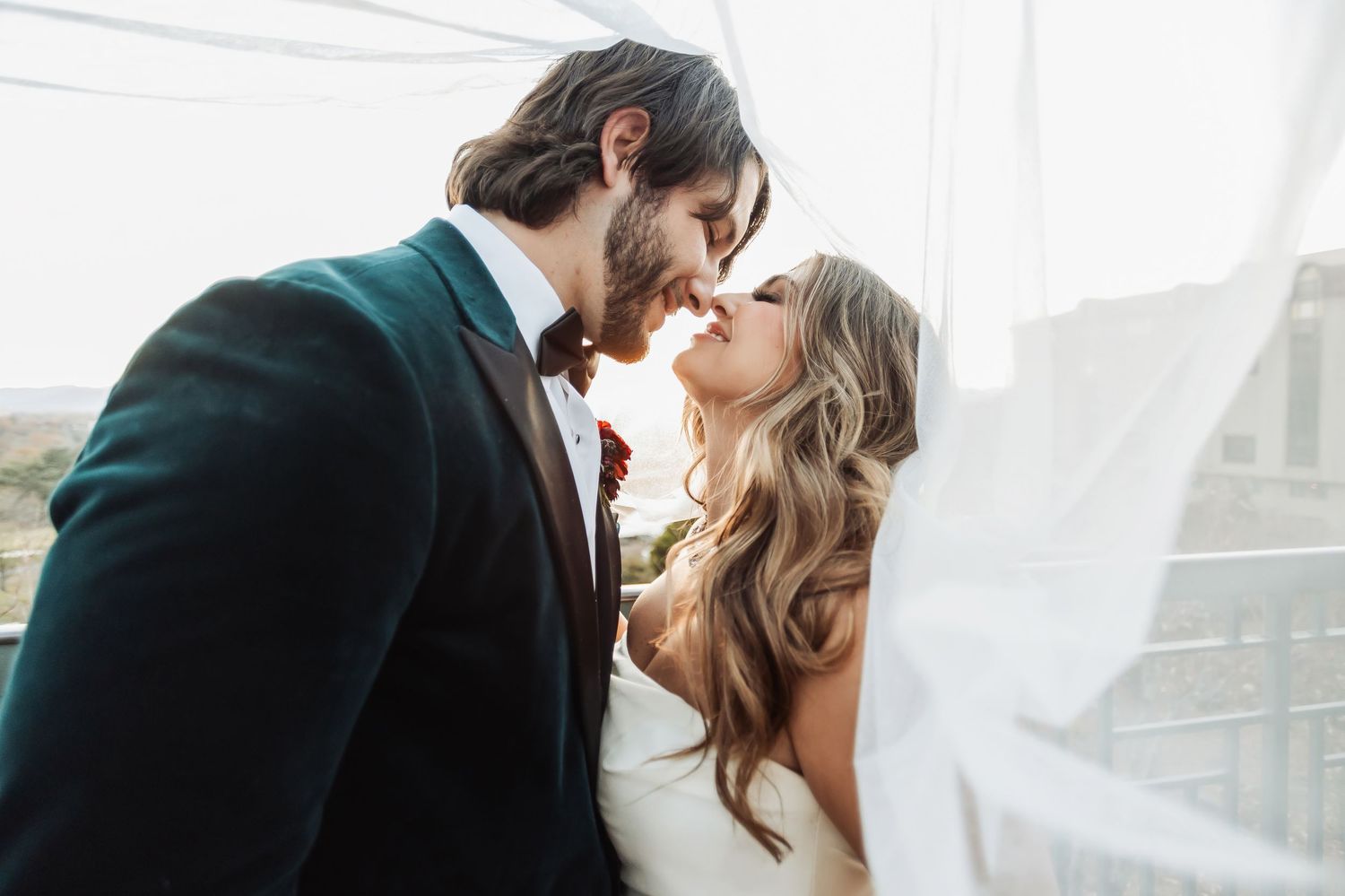 A romantic black and white photo sequence shows a wedding couple embracing on a grassy hillside as the bride's veil flows in the wind.