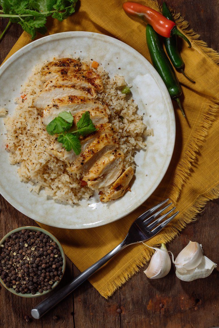 White plate with seasoned rice dish garnished with herbs and spices on golden cloth.