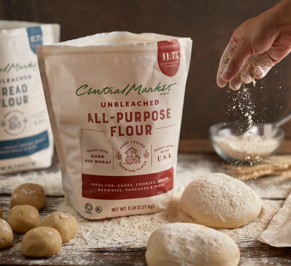 Various bags of all-purpose flour and baking ingredients arranged on a wooden surface.